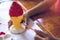 Close up hand of little children painting plaster ice cream cone with red and yellow