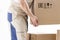 Close-up of hand of loader holding cardboard box isolated on white background. Loader picks up box. Mover holds cardboard box