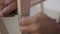 Close-up of the hand of a man going to tighten a nut with a tool. There is a wooden piece of furniture in the picture