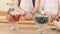 Close-up of the hand of a man and woman who prepare a fruit salad with strawberries.