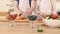 Close-up of the hand of a man and woman who prepare a fruit salad with strawberries.