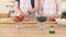 Close-up of the hand of a man and woman who prepare a fruit salad with strawberries.