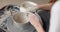 Close-up of the hand of a master potter working on a potter's wheel, forming a bowl of clay. Slow motion