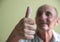 Close-up of a hand with an outstretched thumb. A positive Caucasian pensioner shows a thumbs up with optimism. Selective focus