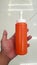 Close up hand of person holding ketchup or tomato sauce with white tile floor background.