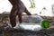 Close up Hand picking up clear plastic bottle water drink with a green cap on the road in the park at blurred background, Trash