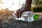 Close up Hand picking up clear plastic bottle water drink with a green cap on the road in the park at blurred background, Trash