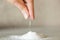 A close-up of a hand pours a hill of salt. microplastic problem in salt.