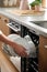 Close-up of a hand putting a dirty ceramic plate in the dishwasher. The concept of household and useful technology.