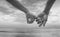 Close up hand of senior couple hook each other\'s little finger together near seaside at the beach,black and white picture