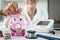 Close up,Hand of senior woman putting coins into piggy bank with coins stack, stethoscope,blood pressure monitor,old elderly