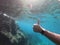 Close up of hand with smart watch underwater in the sea with rocks at the bottom. Thumbs up, while exercising abstract