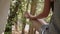 Close up hand of sporty young blonde woman in denim overall sits at exit of tent in nature and does asana. Morning