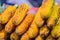 Close up hand of street food vendor while grilling for mixed sweet corn butter. Cook is grilling and sprinkling salt, sugar and b