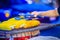 Close up hand of street food vendor while grilling for mixed sweet corn butter. Cook is grilling and sprinkling salt, sugar and b