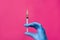 Close-up of a hand with a syringe on a pink background, concept of health, cosmetology, treatment and recovery