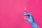 Close-up of a hand with a syringe on a pink background, concept of health, cosmetology, treatment and recovery