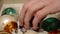 Close up of hand taking out shiny aged Christmas speheres from box. Detail of Man takes out vintage brightly XMas balls for decor