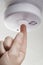 Close Up Of Hand Testing Domestic Smoke Alarm