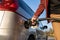 Close up on hand of unknown caucasian man hold black gas pump nozzle pouring gasoline into the fuel tank refueling petroleum to