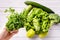 Close up on hand of unknown caucasian man holding green parsley above table with various vegetables - bright filter raw vegan and