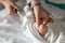 Close up on hand of unknown woman holding leg of her newborn baby - caucasian mother dressing or undressing her little baby on the