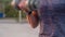 Close-up hand of unrecognizable muscular young sportsman lifting dumbbell during summer evening workout outdoor.