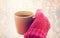 Close up of hand in winter mitten holding tea mug