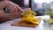 Close-up of hand of woman cutting fresh bell pepper using kitchen knife on board.