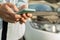 Close up hand of woman using smartphone and blur of her broken car parking on the road. Contacting car technician or