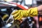Close-up of hand in yellow glove cleaning car with microfiber cloth, Selective focus hands in gloves of expert technician electric