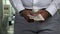 Close up handcuffed businessman holding hundred dollar bills.
