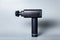 Close up handheld wireless professional therapeutic shock massage gun on gray background