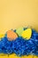 Close up Handmade paper easter eggs in blue paper nest on yellow backdrop