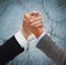 Close up of hands armwrestling over concrete wall