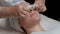 Close-up. The hands of the beautician in gloves with white napkins cleans the face and neck of a beautiful girl. Stage of the proc