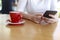 Close up hands of beautiful young woman holding mobile, smart phone sitting in cafe. Soft focus hands of women holding and use