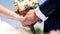 Close-up of hands of the bride and groom with bouquet