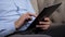 Close up hands businessman uses tablet sitting on couch at home office