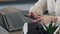 Close-up of hands of businesswoman who typing text on the phone with laptop on the background