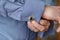 Close-up of hands buttoning a cufflink on the sleeve of a blue shirt.