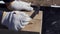 Close up for hands of a carpenter in protective gloves writing something on a wooden board. Clip. Joinery works