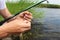 Close-up of the hands of a Caucasian fisherman stringing a worm on the hook of a fishing rod.