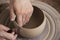 Close-up of the hands of a ceramist working in his potter wheel.