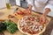 Close-up on the hands of the chef adding tomatoes to the pizza toppings. Vegan food