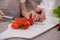 close-up of the hands of the child and mother cut cherry tomatoes on porcelain board preparing healthy vegetable salad