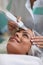 Close up of hands of cosmetologist with professional ultrasonic equipment for cleaning skin