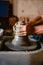 Close-up of the hands of the craftsman while creating a ceramic pot on the lathe