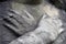 A close up hands crossed over the chest of a statue of a Victorian graveyard angel. With a shallow depth of field and blurred