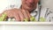 Close-up of hands of an elderly man caring for house plants. A pensioner processes seedlings. Selective focus, man`s face out of f